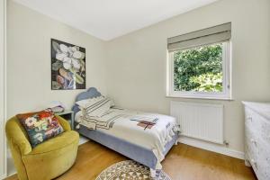 a bedroom with a bed and a chair and a window at 3 bdrm Notting Hill Mews house - 2 balconies in London