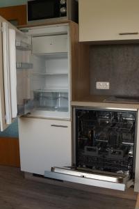 施呂瑟爾費爾德的住宿－Fewo "Elsa" Reichmannsdorf - Brötchenservice，厨房设有开放式冰箱,厨房的门是敞开的。