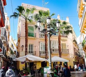 una calle con palmeras frente a un edificio en www Casa Quili Cádiz com en Cádiz