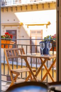 a wooden table with two wine glasses on a balcony at Natoli Apartments in Palermo