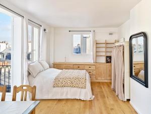 Schlafzimmer mit einem Bett, einer Kommode und Fenstern in der Unterkunft Saint Sulpice Towers in Paris