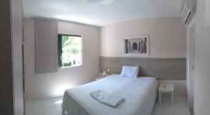 une chambre blanche avec un lit et une fenêtre dans l'établissement GENIPABU CLUB HOUSE Guarajuba, à Camassari