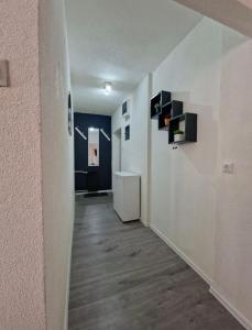a hallway with white walls and wood floors and a room at Black & White Modern Apartment in Tuzla +1 photo