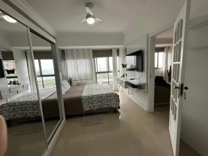 1 dormitorio con cama, escritorio y espejo en Apartamento Sun Barra Tijuca frente Mar, en Río de Janeiro