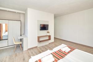 a white bedroom with a bed and a chair at Relax Larrisa Studio in Primorsko