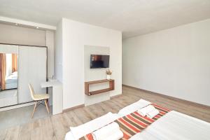 プリモルスコにあるRelax Larrisa Studioの白いベッドルーム(ベッド1台、椅子付)