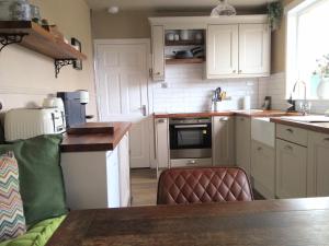 una cocina con armarios blancos y un sofá. en Auld Tom's Rest en St Andrews