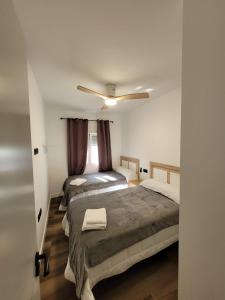 um quarto com duas camas e um ventilador de teto em Caímachado em Cádis