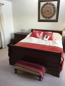 - une chambre avec un grand lit et des oreillers rouges dans l'établissement Lower Penrose Old Farmhouse Cottage, à Launceston
