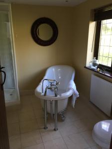 La salle de bains est pourvue d'une baignoire, d'un lavabo et d'un miroir. dans l'établissement Lower Penrose Old Farmhouse Cottage, à Launceston