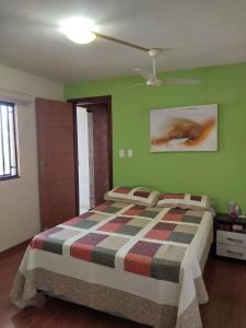 a bed in a bedroom with green walls and a ceiling at Casa com Piscina in Serra