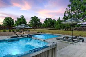 a large swimming pool with two umbrellas and two benches at Hot Tub Pool + Firepit + Gameroom ~ Guesthouse in Manor