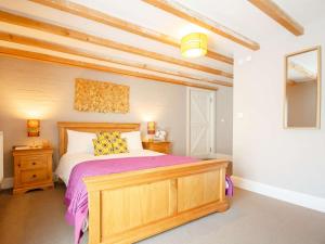 a bedroom with a wooden bed with purple sheets at 1 bed in Bala 52510 in Corwen