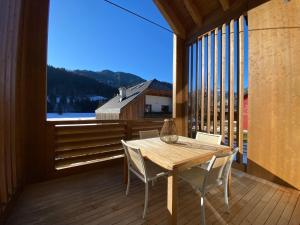 einen Holztisch und Stühle auf einem Balkon mit einem großen Fenster in der Unterkunft Luxury Chalet in the Tarvisio mountains in Camporosso in Valcanale