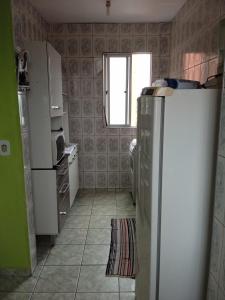 eine kleine Küche mit einem Kühlschrank und einem Fenster in der Unterkunft Apartamento para temporada in Mongaguá