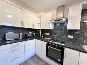 a kitchen with white cabinets and a stove top oven at Densham House by Blue Skies Stays in Stockton-on-Tees