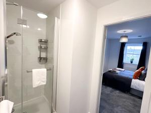 a bathroom with a walk in shower next to a bed at Densham House by Blue Skies Stays in Stockton-on-Tees