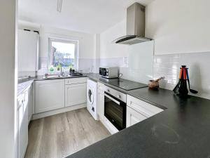 a kitchen with white cabinets and a black counter top at Fewster Apartment - City Centre location with free parking in York