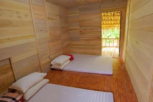 two beds in a room with wooden walls and a window at Homstay Hưng Yên - Long Cốc 