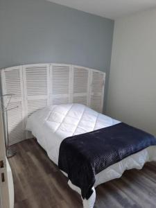 Un dormitorio con una cama blanca con una manta negra. en Appart magnifique avec une vue exceptionnelle OLERON, en La Bernerie-en-Retz