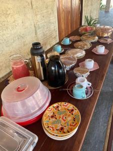 a wooden table topped with plates of food and drinks at Pousada rancho sol nascente in Tutóia