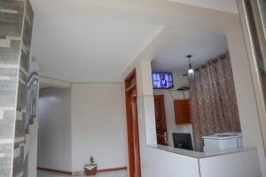 Habitación con TV en la pared y pasillo. en Apollo Inn Fortportal, en Kigarama