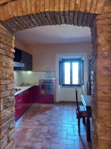 uma cozinha com armários vermelhos, uma mesa e uma janela em Casa Marzocco em Pomarance