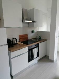 uma cozinha com armários brancos, um lavatório e um fogão em Monolocale Ostia locaz.turistica em Lido di Ostia