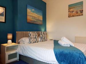 a bedroom with a bed and a blue wall at Salt Marsh Apartment in Tywyn