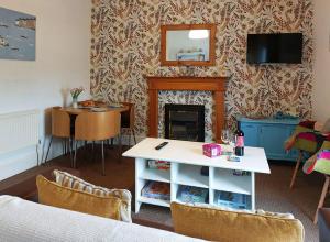 uma sala de estar com uma lareira e uma mesa em Salt Marsh Apartment em Tywyn