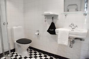 a white bathroom with a toilet and a sink at Akademihotellet in Uppsala