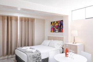 Habitación blanca con cama y mesa en Residencial Suiza, en Lima