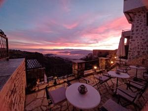 a balcony with tables and chairs and a sunset at Archontiko Anemos in Makrinitsa