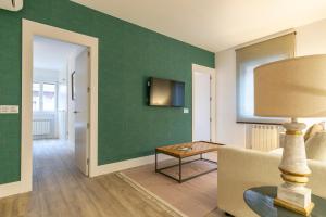 sala de estar con pared verde, sofá y mesa en PLAZA DE CASTILLA Apartments, en Madrid