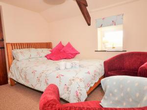 a bedroom with a bed and a red chair at 1 Bed in Torrington 42982 in Petrockstow