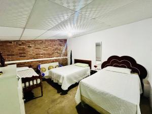 um quarto com 2 camas e uma parede de tijolos em Entre tejas em Concepción de Ataco