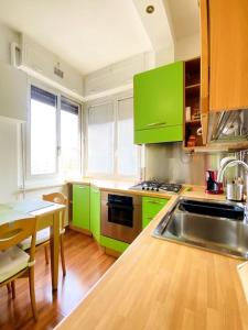 uma cozinha com armários verdes, um lavatório e uma mesa em MHOME APARTMENT - Roma em Roma