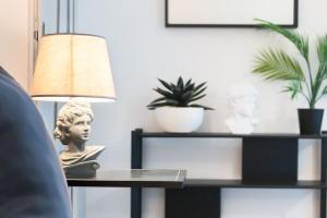 a table with a bust on it next to a lamp at Historical suite - Pieno Centro - Porta nuova- Piazza Castello in Turin