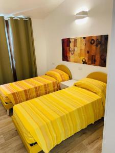 three beds in a room with yellow stripes at Mauris Home in Tortolì