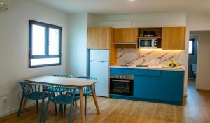 uma cozinha com armários azuis e uma mesa e cadeiras em Apartamentos Sol y Mar II em Cala en Blanes