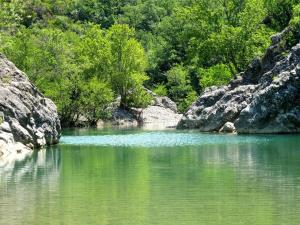 a body of water with some rocks and trees at Casa Marzocco in Pomarance