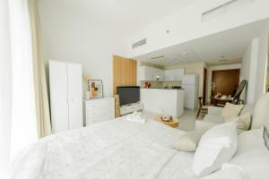 a white bedroom with a white bed and a kitchen at Chic Apartment Dubai Marina in Dubai