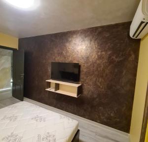 1 dormitorio con pared y TV. en Fully furnished Apartment en Varna