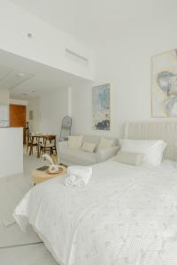 a white bedroom with a large bed and a couch at Chic Apartment Dubai Marina in Dubai