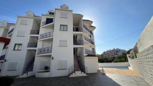 a white apartment building with a pool in front of it at Kione Sol y Mar in Alcossebre +3 photos