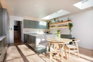 a kitchen with a wooden table and a table and chairs at Veeve - A Symphony in Green in London
