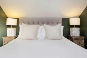 a bedroom with a white bed with two lamps at Veeve - A Symphony in Green in London