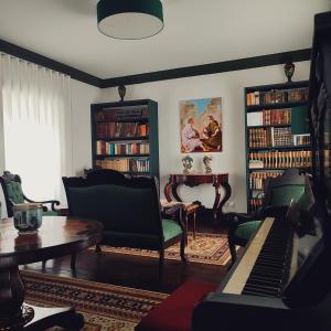 ein Wohnzimmer mit einem Klavier und Bücherregalen in der Unterkunft Quinta dos Mistérios- Turismo de Habitação in Fajã de Santo Amaro
