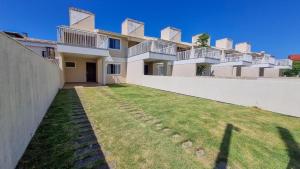 a large white building with a grass yard at Residencial Ferrugem Beira Mar in Garopaba