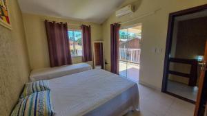 a bedroom with two beds and a view of a balcony at Residencial Ferrugem Beira Mar in Garopaba